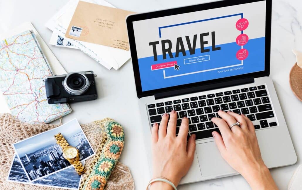 Ricerca di viaggi online su laptop con mappa, fotocamera e accessori di viaggio, promozione digitale per il settore turistico